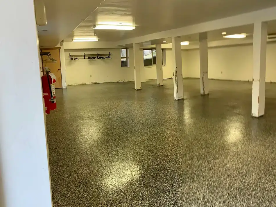 An after photo of an empty basement with a newly coated and polished concrete floor.
