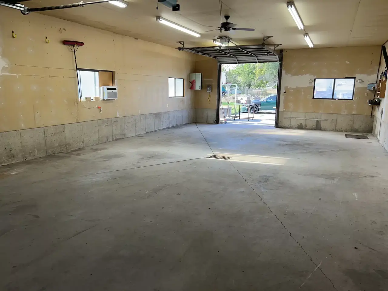 A before photo of an empty warehouse with a rugged-looking concrete floor and open window.