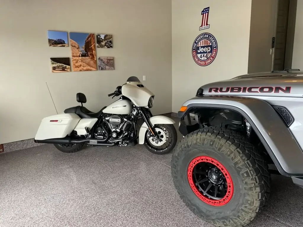 A garage room with a coated concrete floor. A motorcycle and a gray jeep is parked inside.