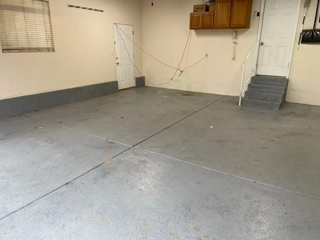 A before photo of a white room with a grimy tiled concrete floor.