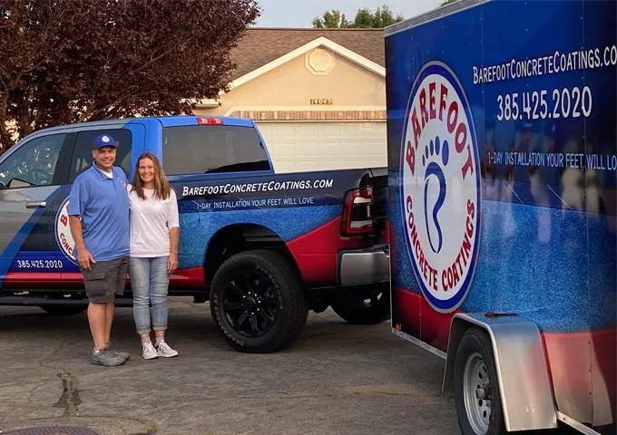 Brian, wearing a blue shirt, and his wife, in white, pose for a photo with their business fleet in the background.