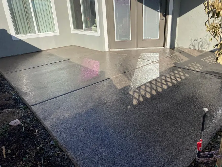 An after photo of a gray house with professionally coated and polished concrete patio.
