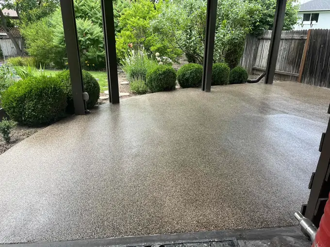 An after photo of a coated and polished concrete patio connected to a lush garden
