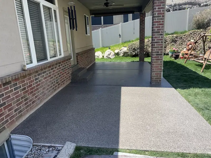 An after photo of a coated concrete patio with a wooden swing in front.