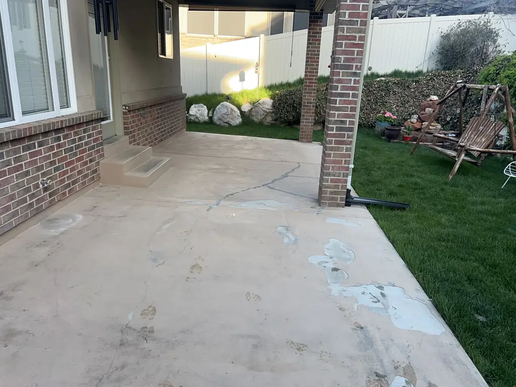 A before photo of a house with a rugged-looking concrete patio and steps.