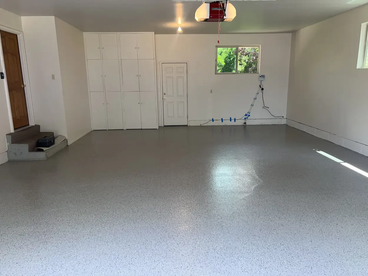 An after photo of an empty garage with white wall and a professionally polished concrete floor.