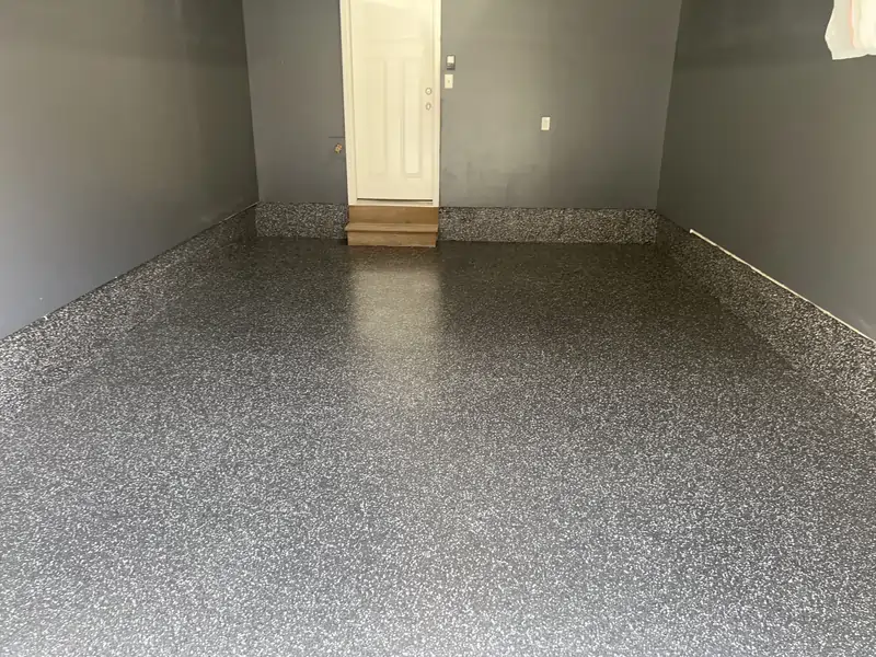 An after photo of an empty garage with a fully coated and polished concrete floor and gray walls.