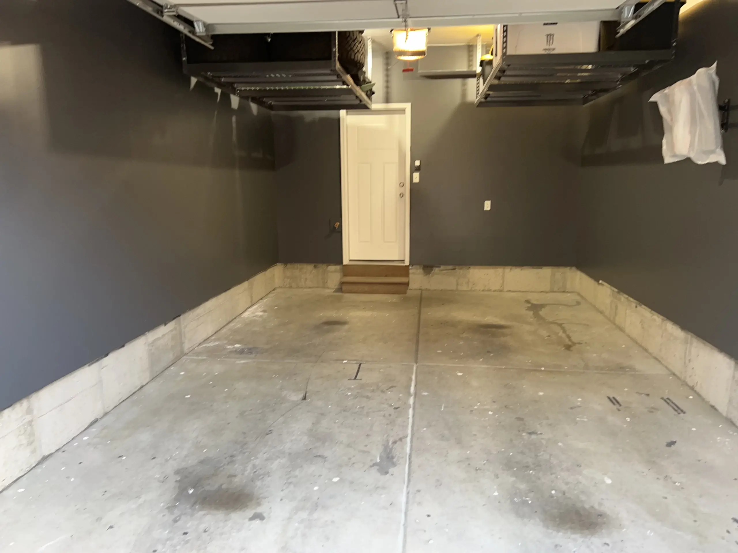 A before photo of an empty garage with a rugged-looking concrete floor and gray walls.