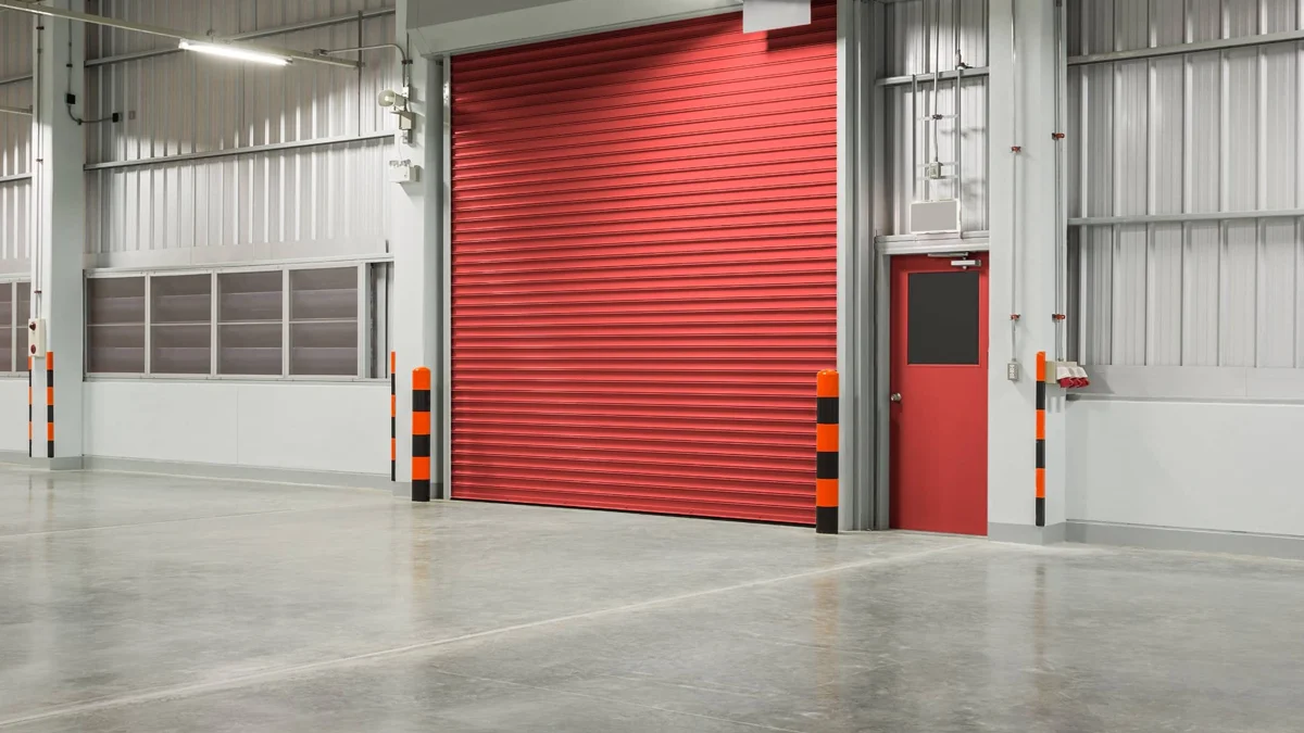 A polished concrete floor with a red roller door in a warehouse.