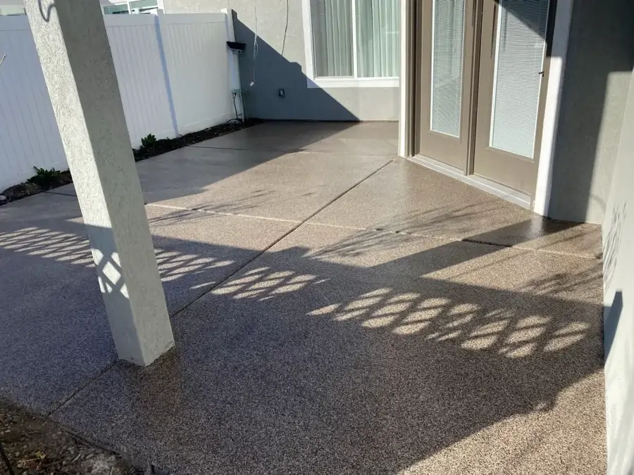 A gray house with a polished and coated concrete patio.