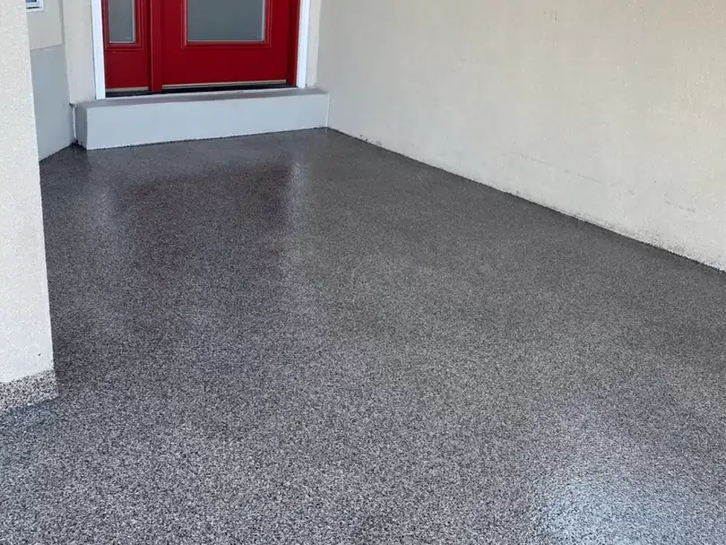 A fully coated concrete floor in front of a red door.